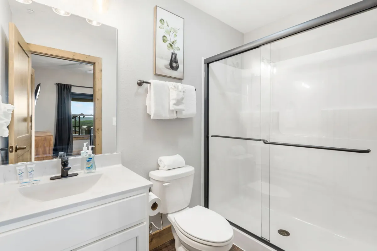 A modern, spa-like bathroom with a sleek vanity sink, a glass-enclosed shower, and tasteful wall art. The serene palette and thoughtful layout evoke a sense of rejuvenation and comfort.
