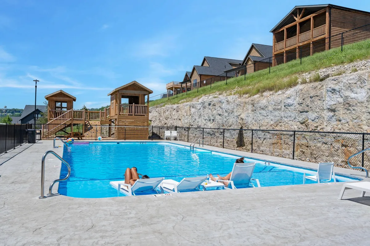 An exterior shot highlighting a swimming pool, wooden playhouses, and lounge chairs, all set within a leisure-focused area. The design is clearly kid-friendly, with space for both play and relaxation, making it ideal for family gatherings and multi-generational enjoyment.