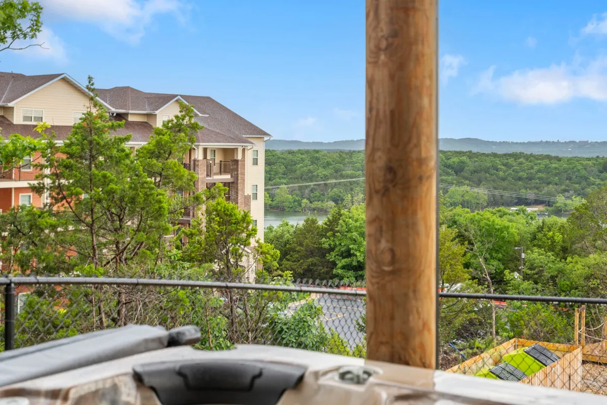 A serene hot tub set on a deck overlooking a beautiful lake, surrounded by lush greenery and distant mountains. The scene suggests peaceful relaxation and connection with nature, with the promise of stargazing from the hot tub or enjoying the sunrise over the water.